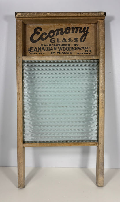 Vintage wooden washboard with a ribbed glass scrubbing surface and a printed wooden header reading 'Economy Glass' and 'Canadian Woodenware Co.'.