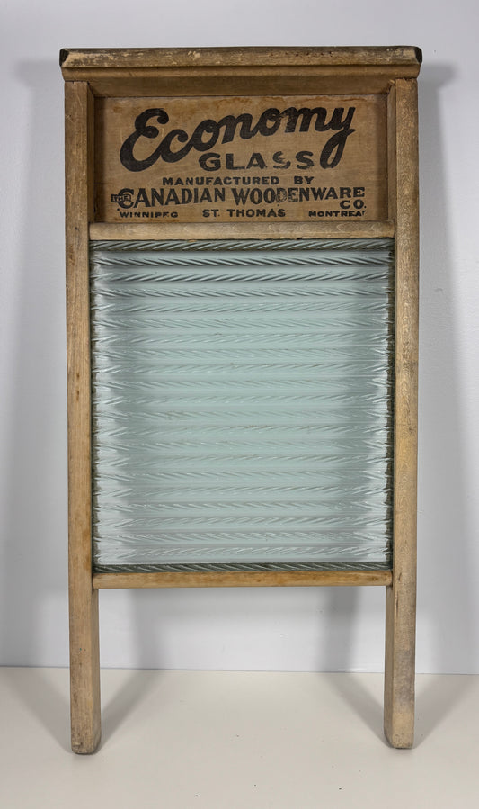 Vintage wooden washboard with a ribbed glass scrubbing surface and a printed wooden header reading 'Economy Glass' and 'Canadian Woodenware Co.'.