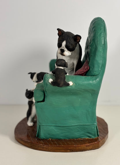 Dog figurine sitting in a green chair with two puppies on a white background