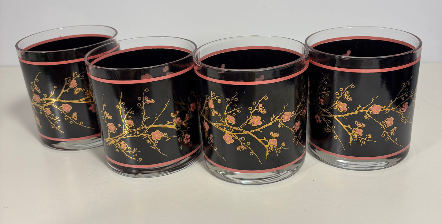 Four glass tumblers with floral design on a black background