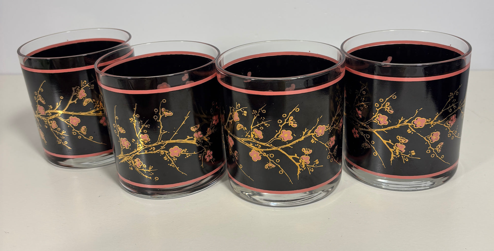 Four glass tumblers with floral design on a black background