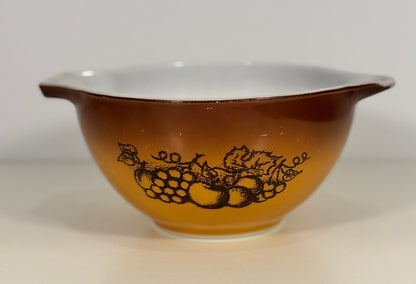 Brown Pyrex mixing bowl with fruit design on a white background