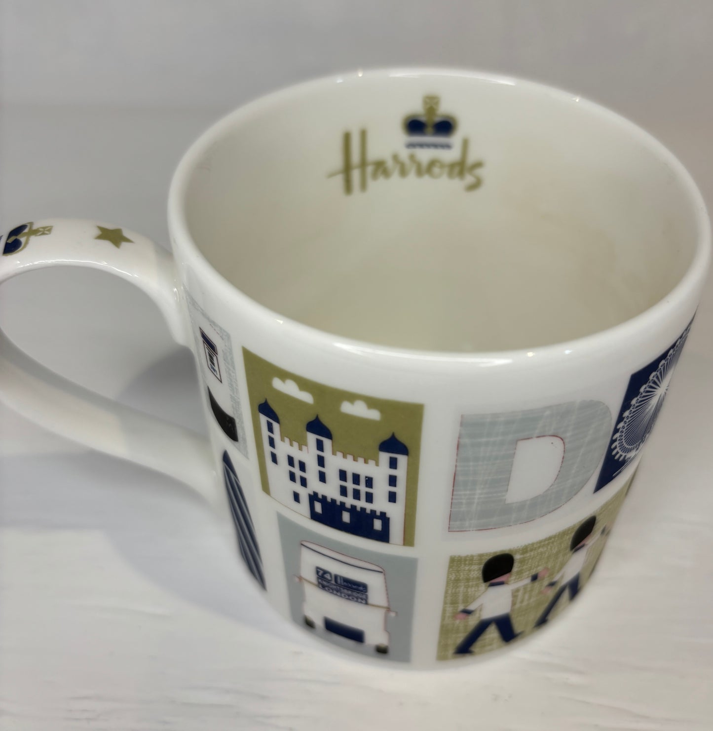 White mug with Harrods branding and decorative design on a white background