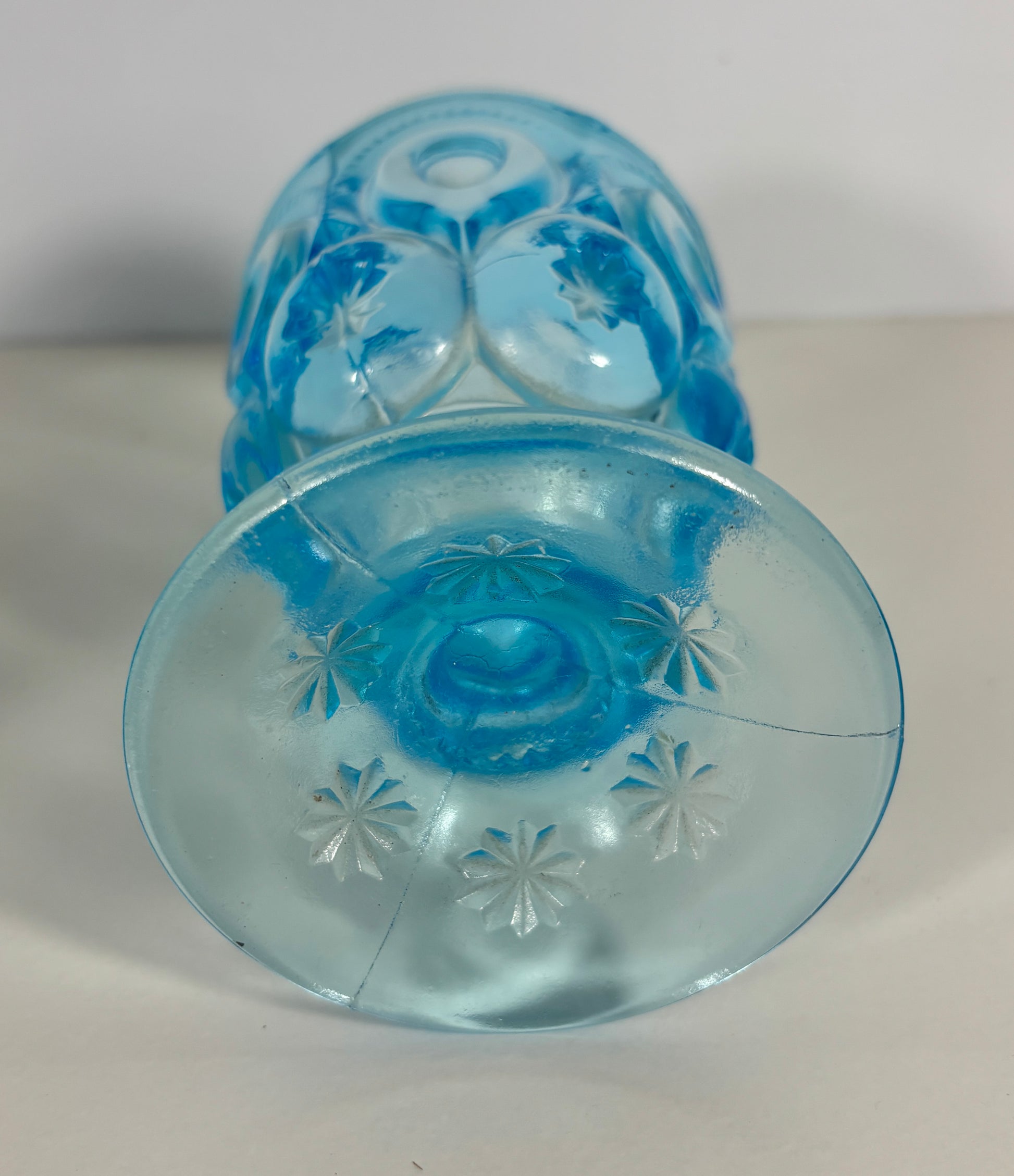 Blue glass candle holder with floral patterns on a white background