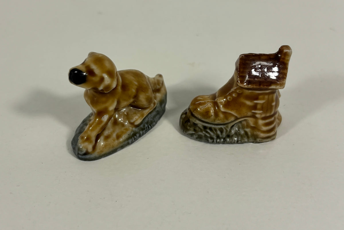 Two small glossy ceramic figurines on a plain light background: a brown dog-shaped object on the left and a brown boot-shaped object on the right.