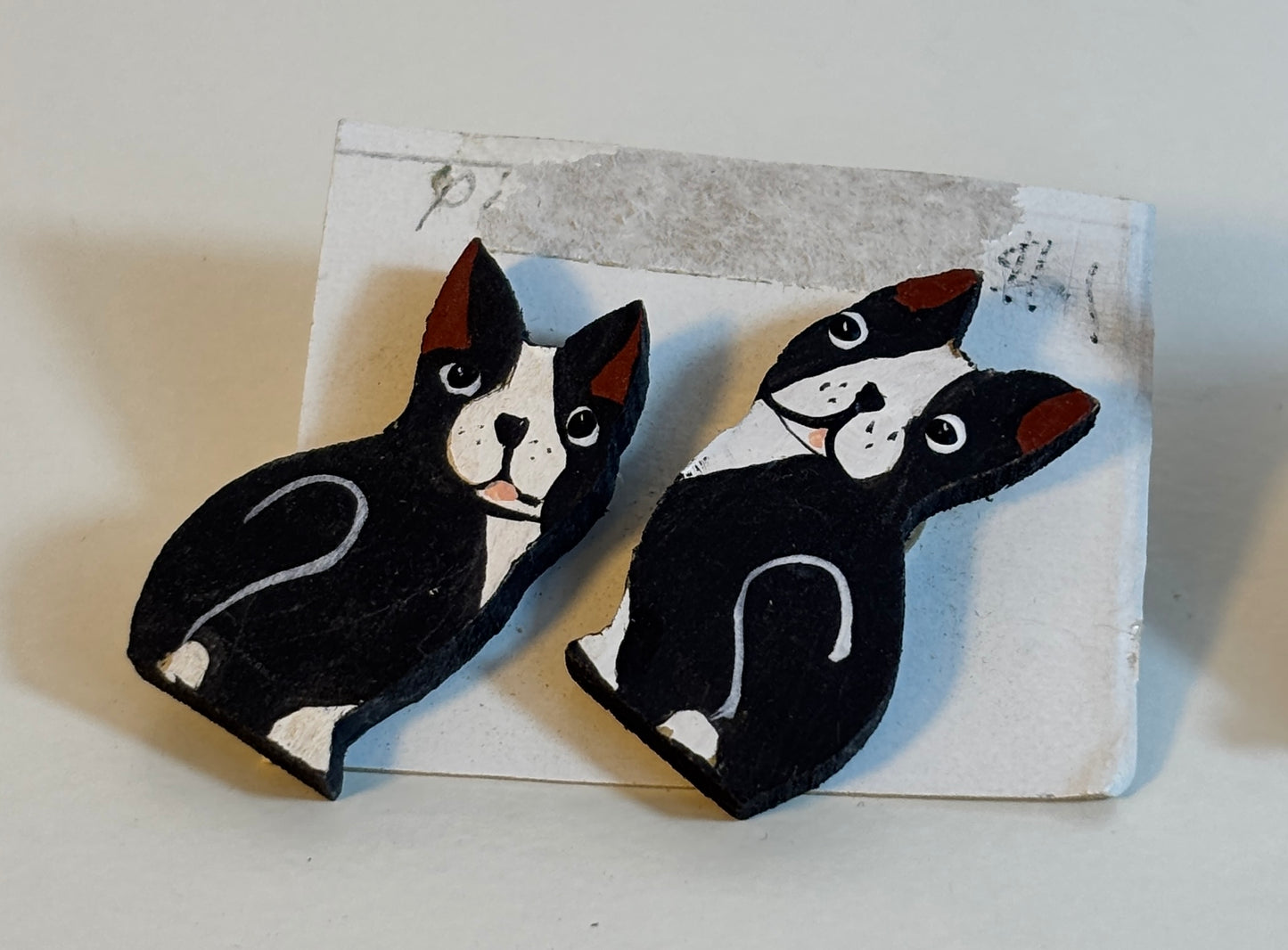 Two black and white dog-shaped earrings on a textured card.