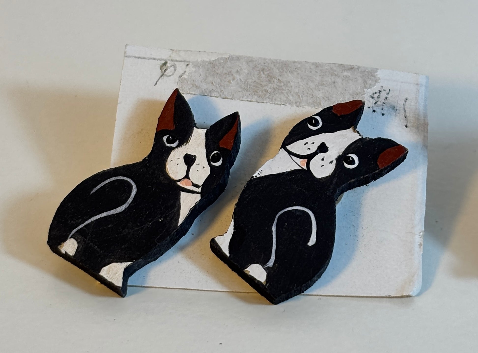 Two black and white dog-shaped earrings on a textured card.