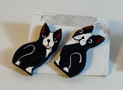Two black and white dog-shaped earrings on a textured card.