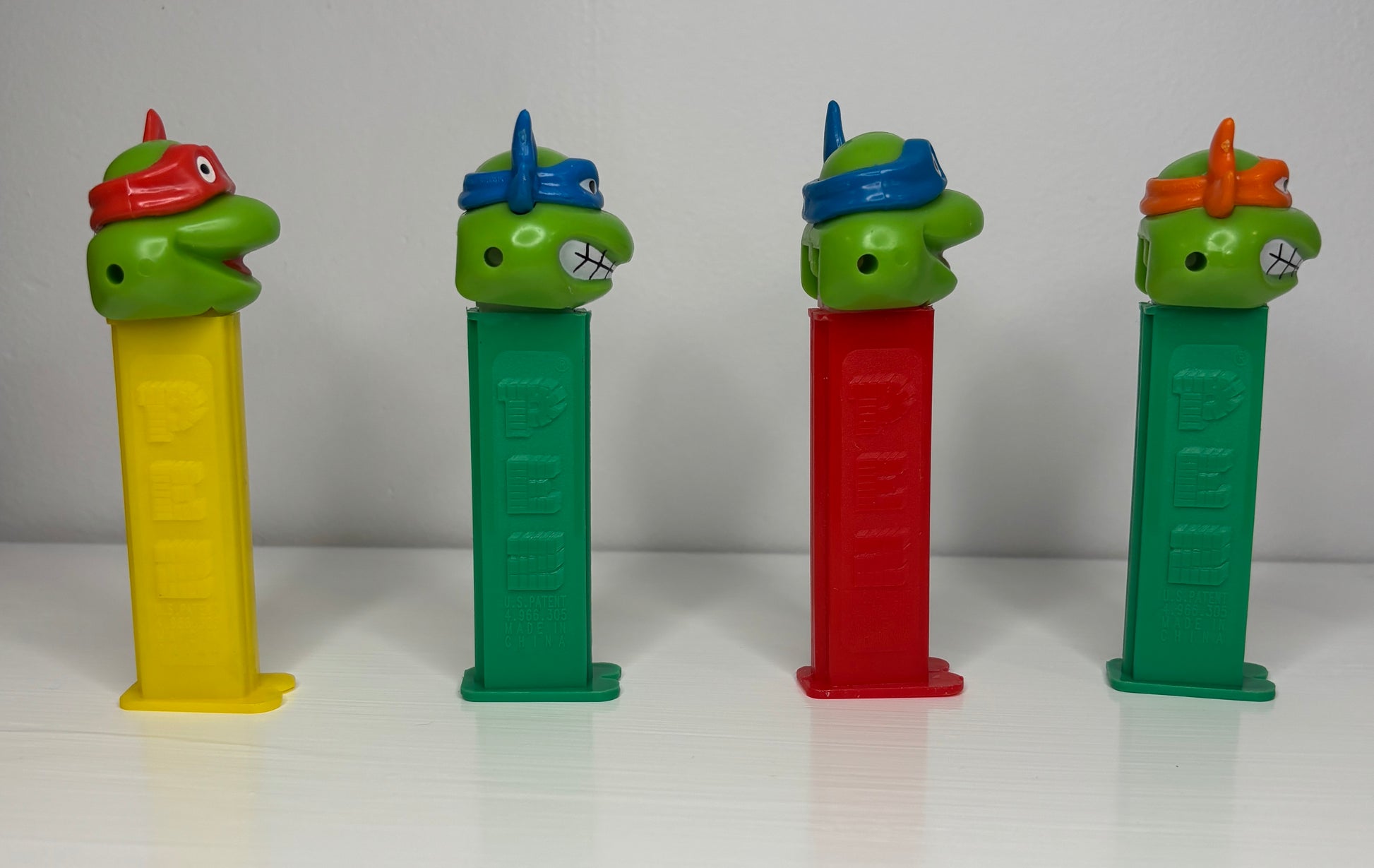 Four PEZ dispensers shaped like cartoon turtles on a white background