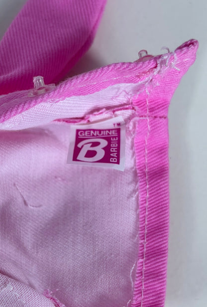 A close-up of a pink Barbie garment, showing the interior lining and a sewn-on 'Genuine Barbie' brand label.