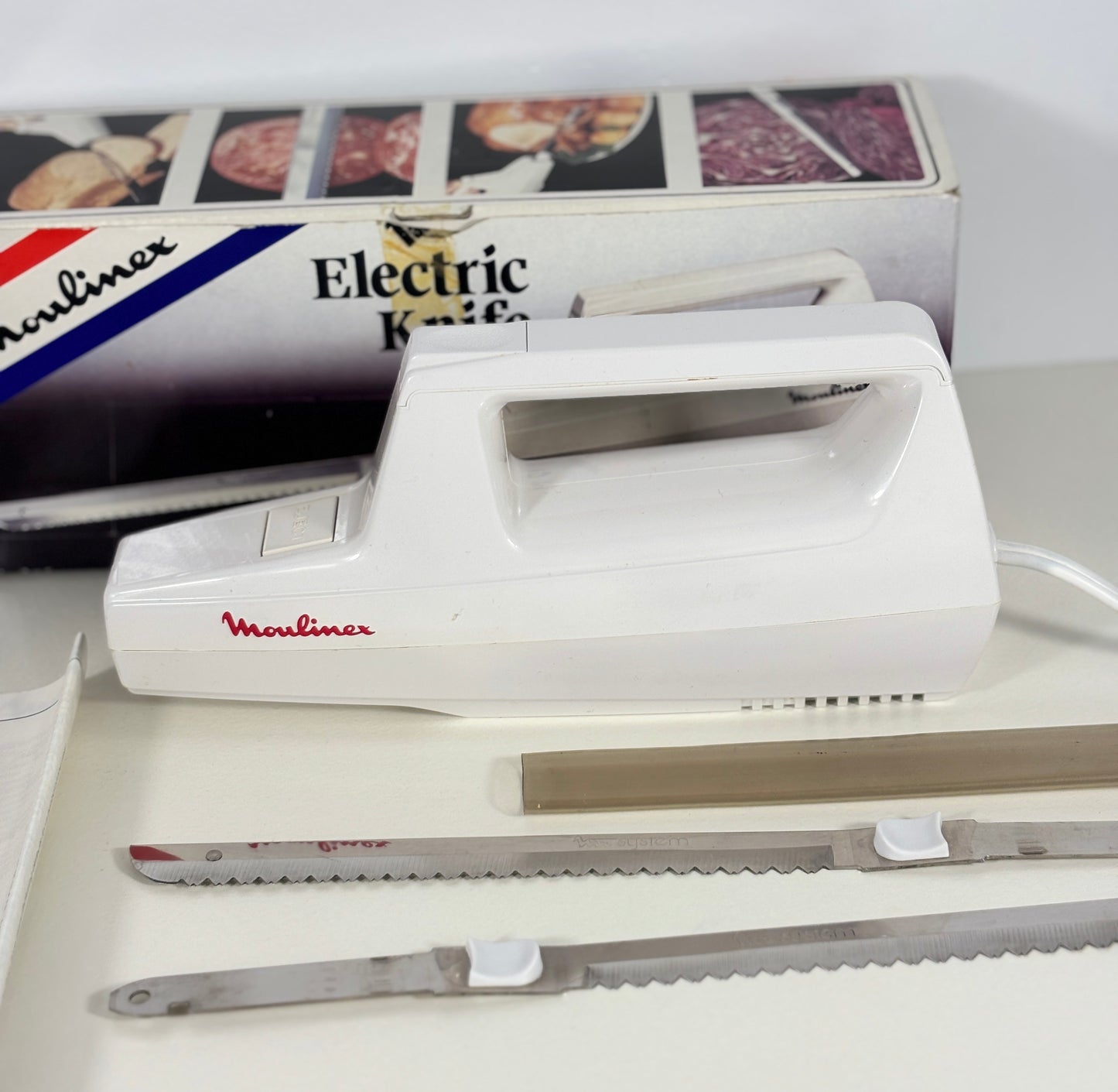 Moulinex electric knife with two blades on a white surface, with the packaging in the background.