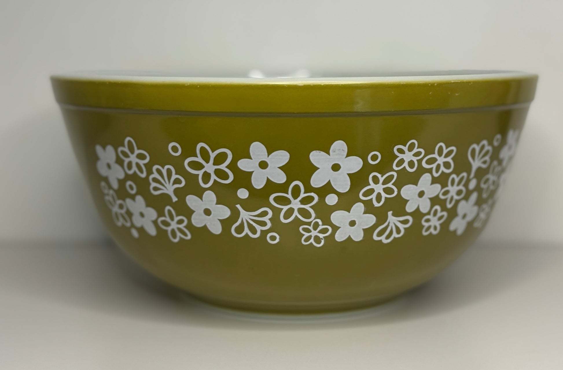 Green bowl with white floral pattern on a white background