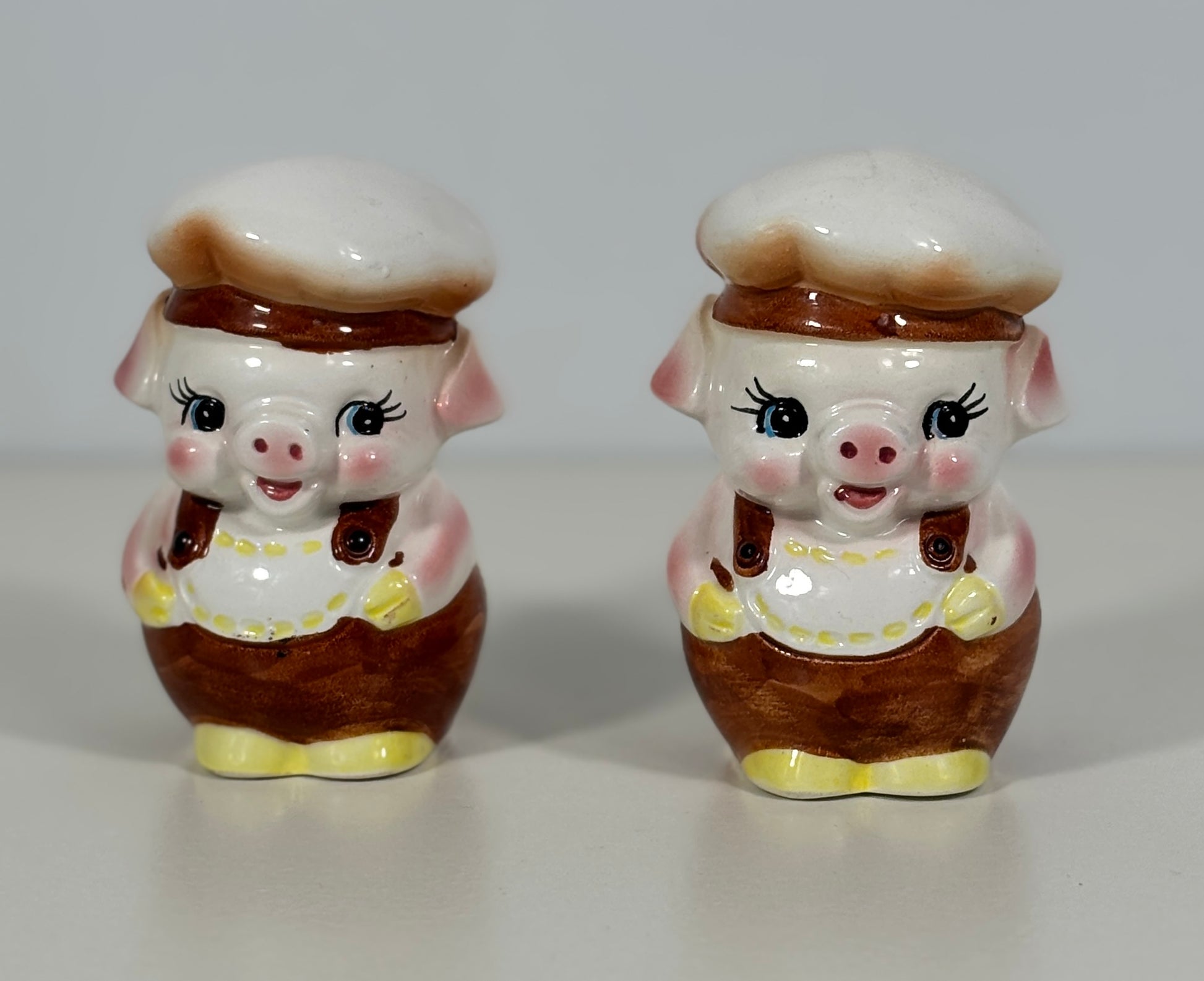 Two ceramic piggy salt and pepper shakers on a white background