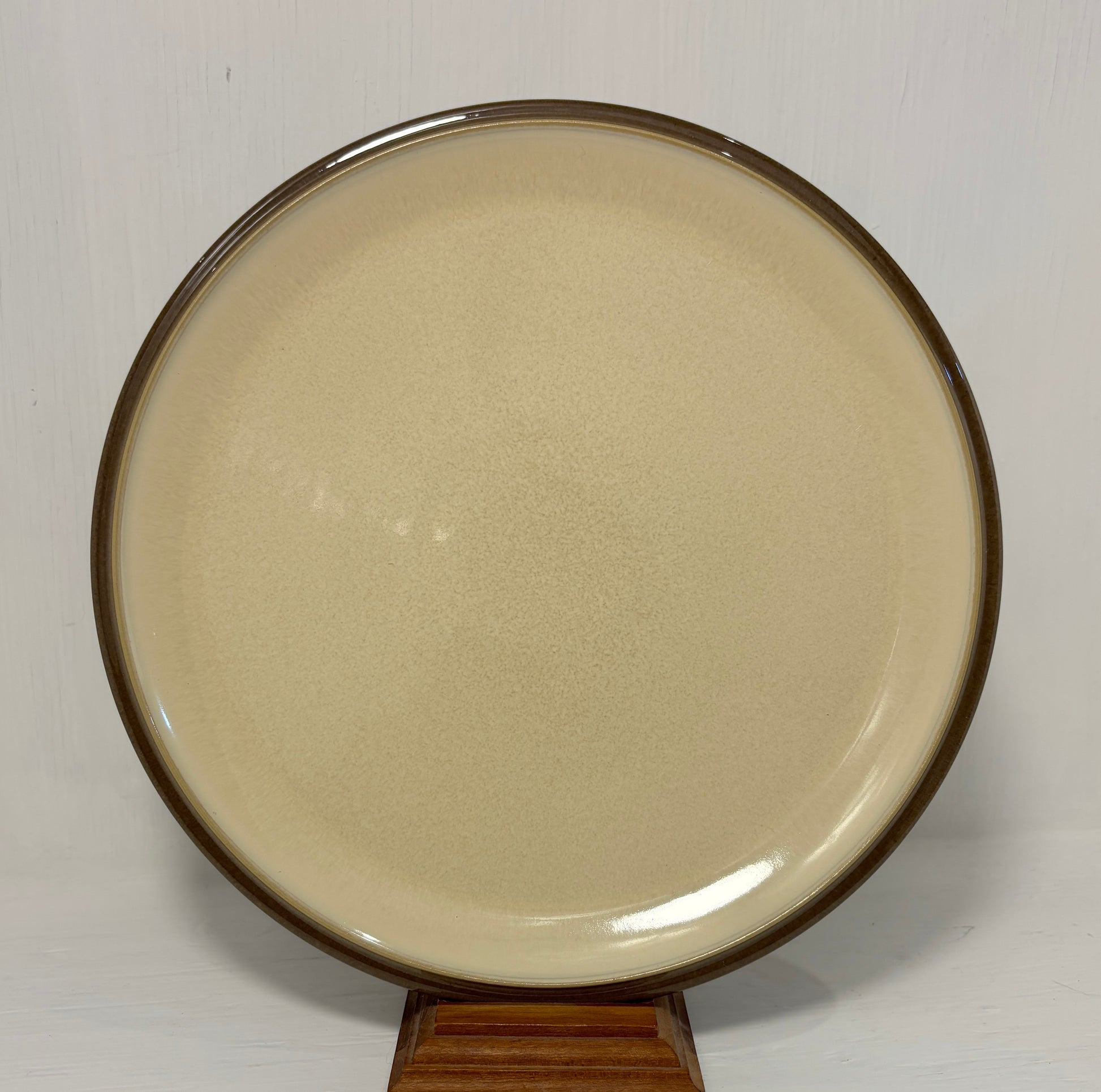 Round beige plate with brown rim on a white background