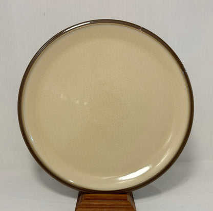 Round beige plate with brown rim on a white background