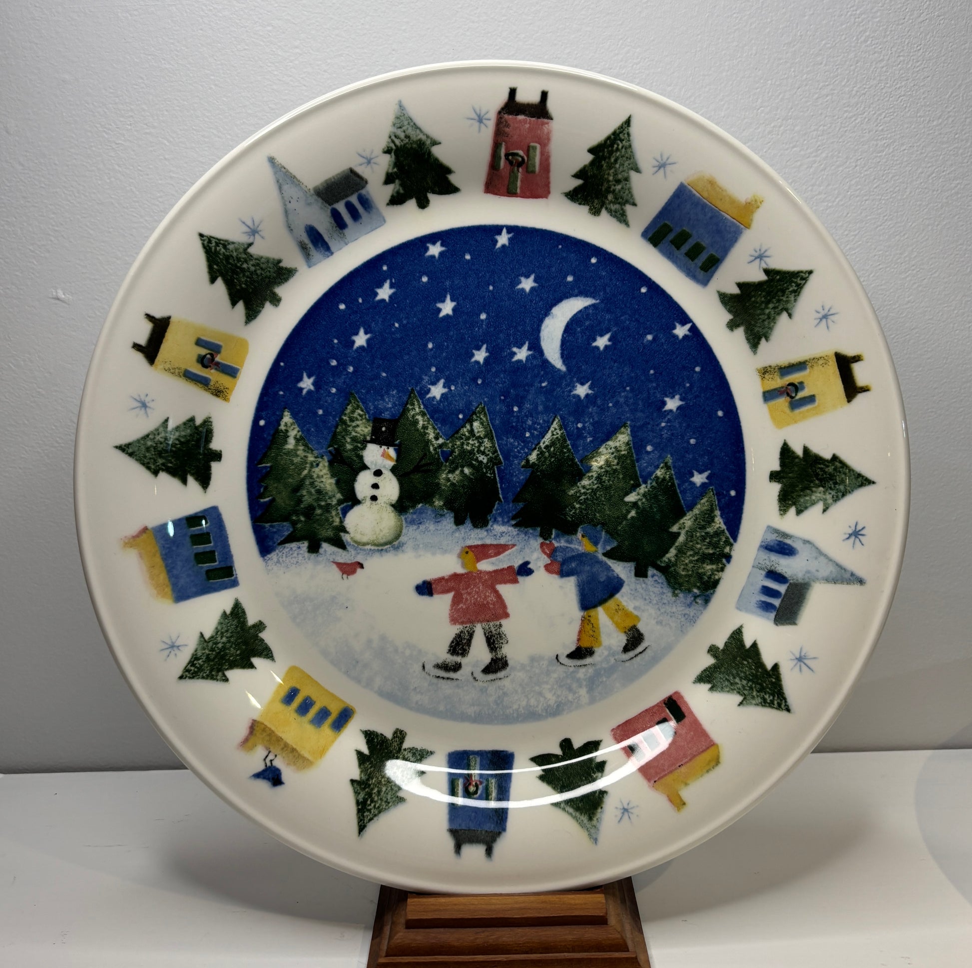 Decorative plate with winter scene of children skating and snowman, on a plain background