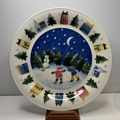 Decorative plate with winter scene of children skating and snowman, on a plain background
