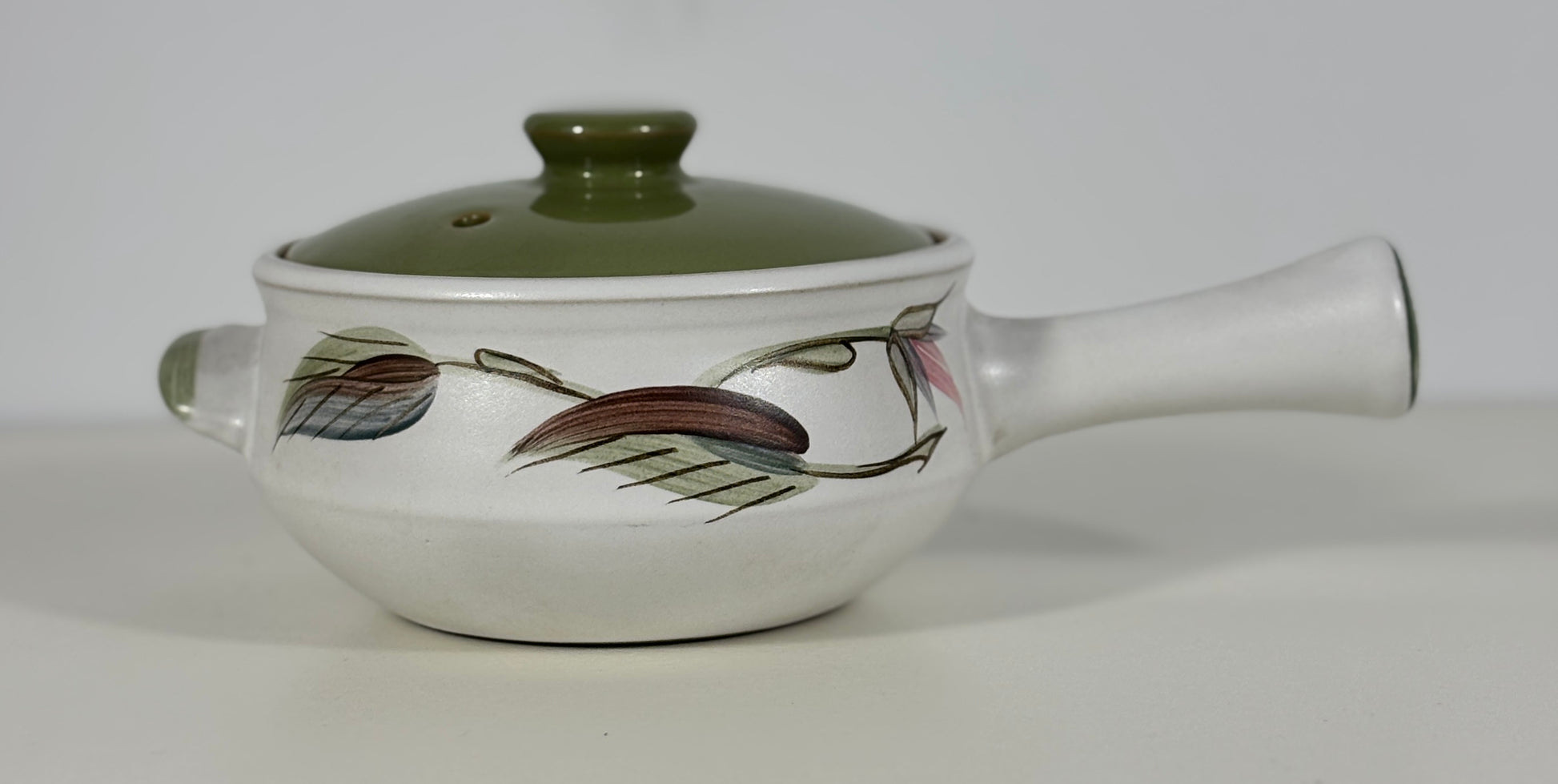 Ceramic pot with a lid and handle on a white background
