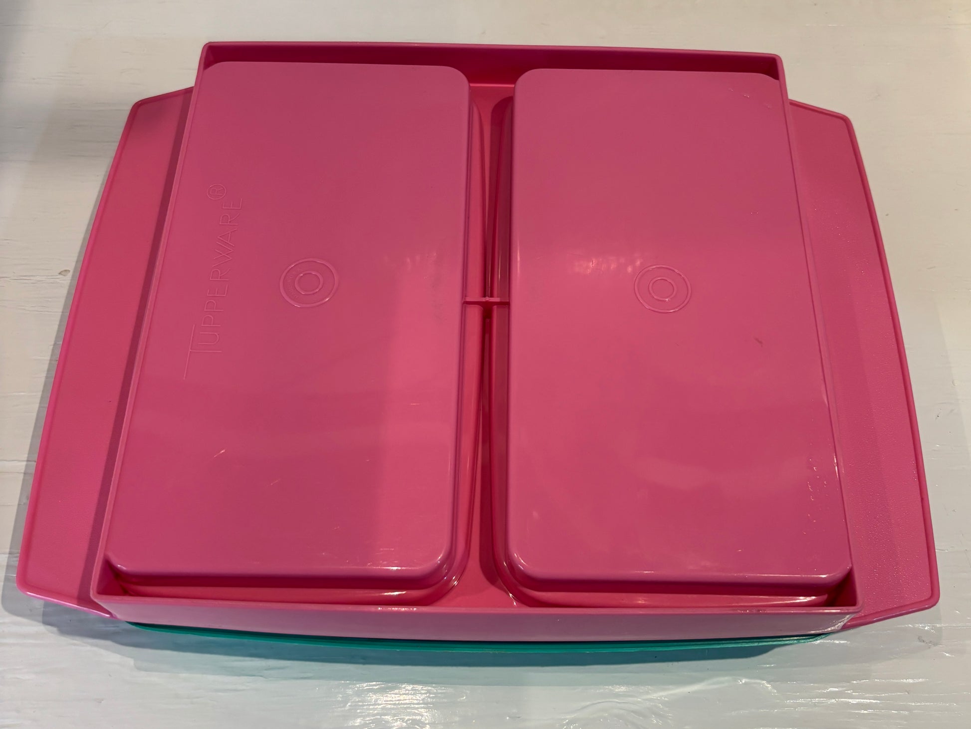 Pink plastic container with two lids on a white background