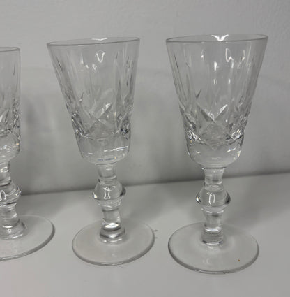 Set of three crystal glasses with intricate designs on a white surface and gray background