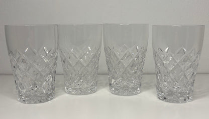 Four crystal tumblers with diamond cut pattern on a white background