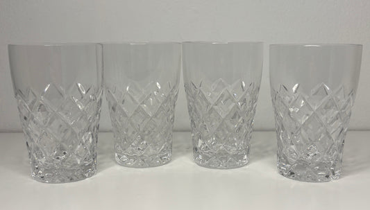Four crystal tumblers with diamond cut pattern on a white background