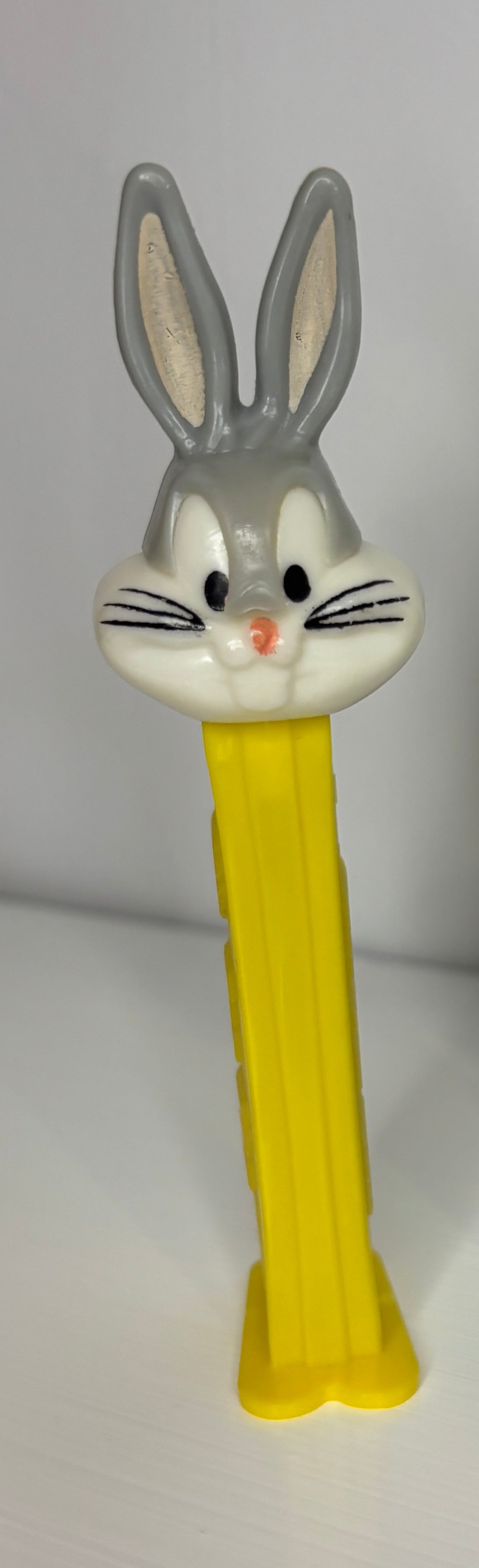 Pez dispenser shaped like a rabbit with a yellow body on a white background