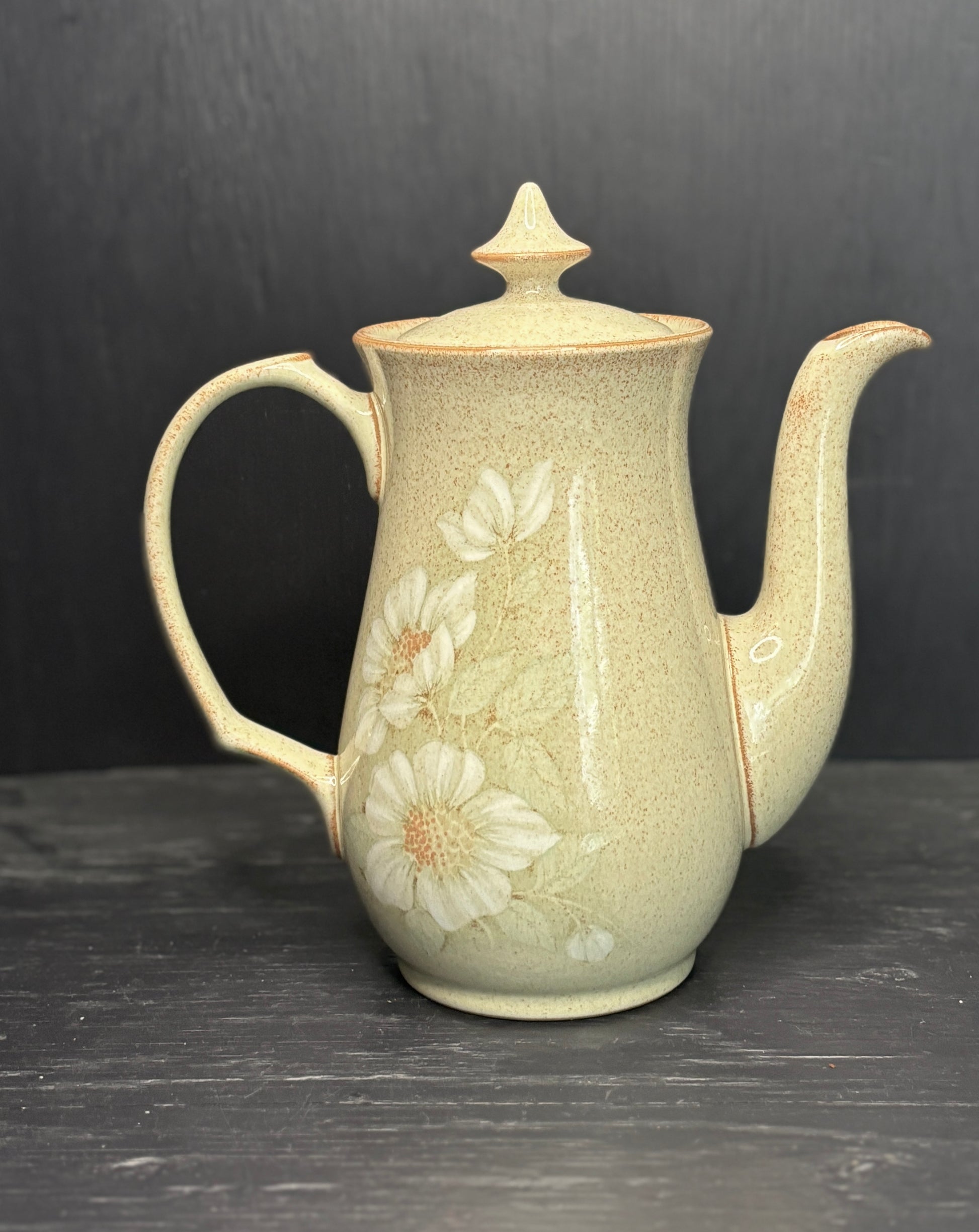 Ceramic teapot with floral design on a dark surface