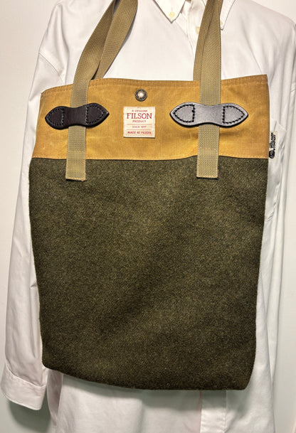 Brown tote bag with green front section and visible Filson label on a white background