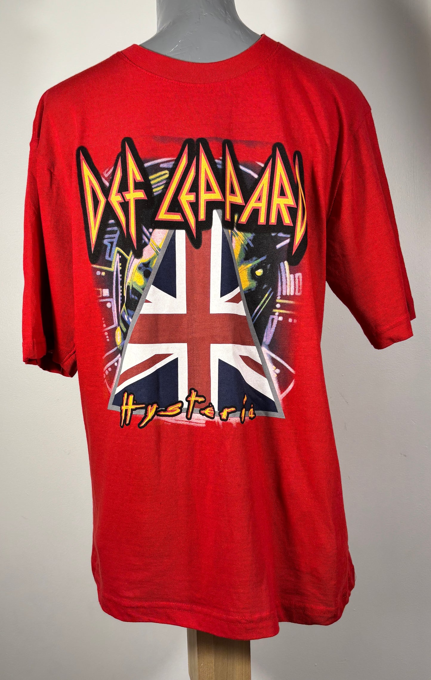 Red Def Leppard t-shirt with band logo and Union Jack design on a mannequin against a gray background