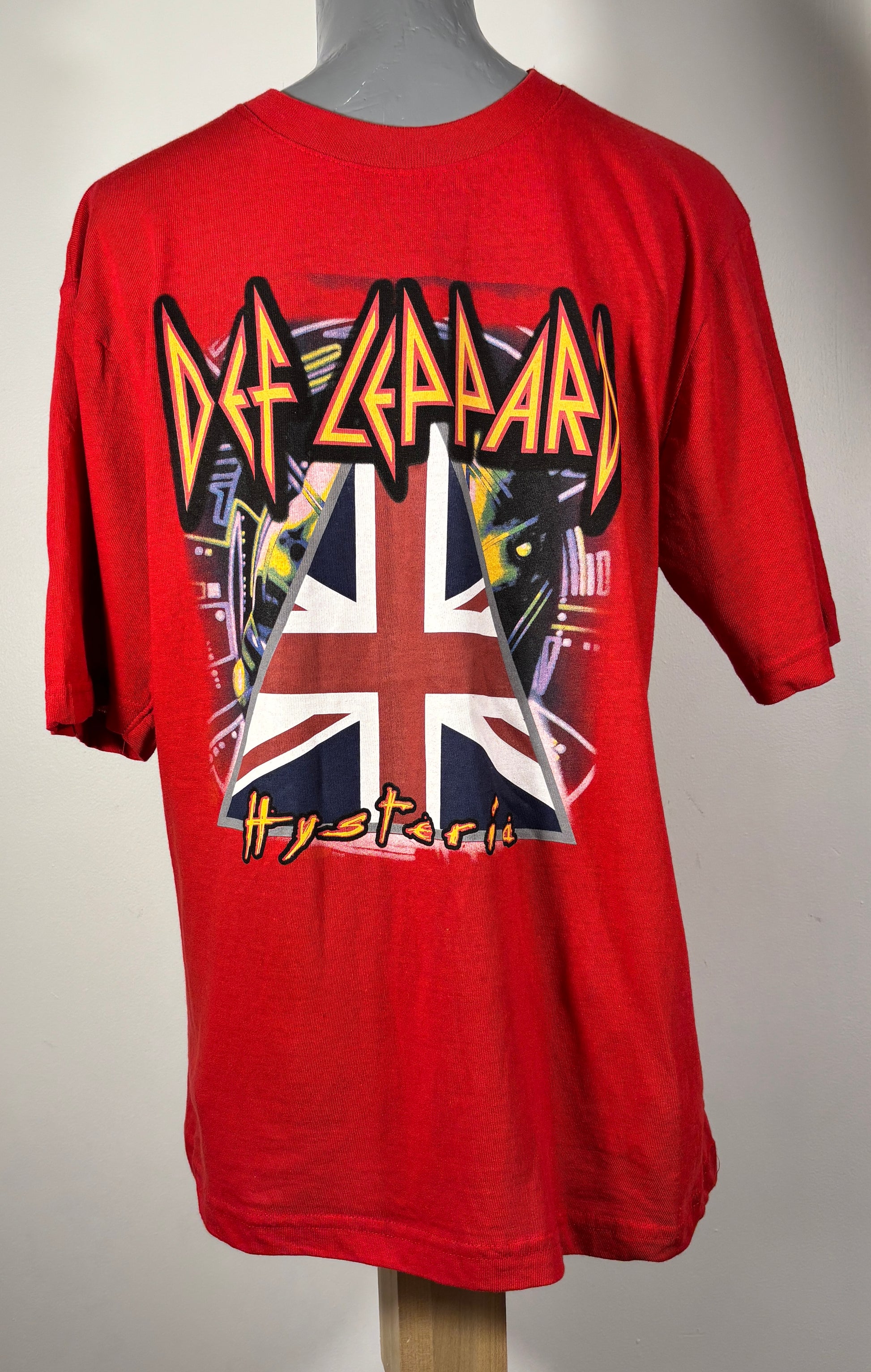 Red Def Leppard t-shirt with band logo and Union Jack design on a mannequin against a gray background