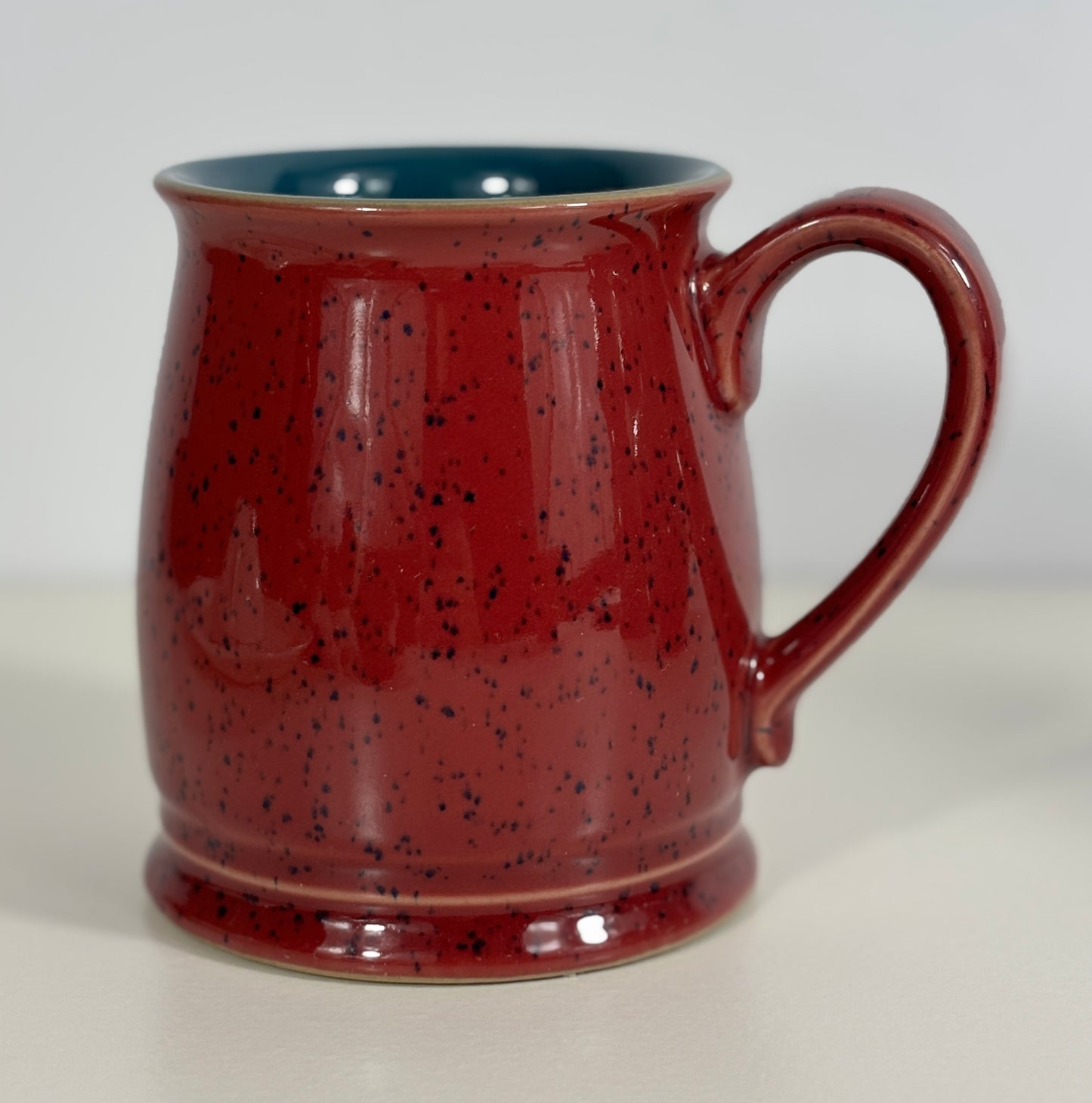 Red speckled mug with a handle on a white background