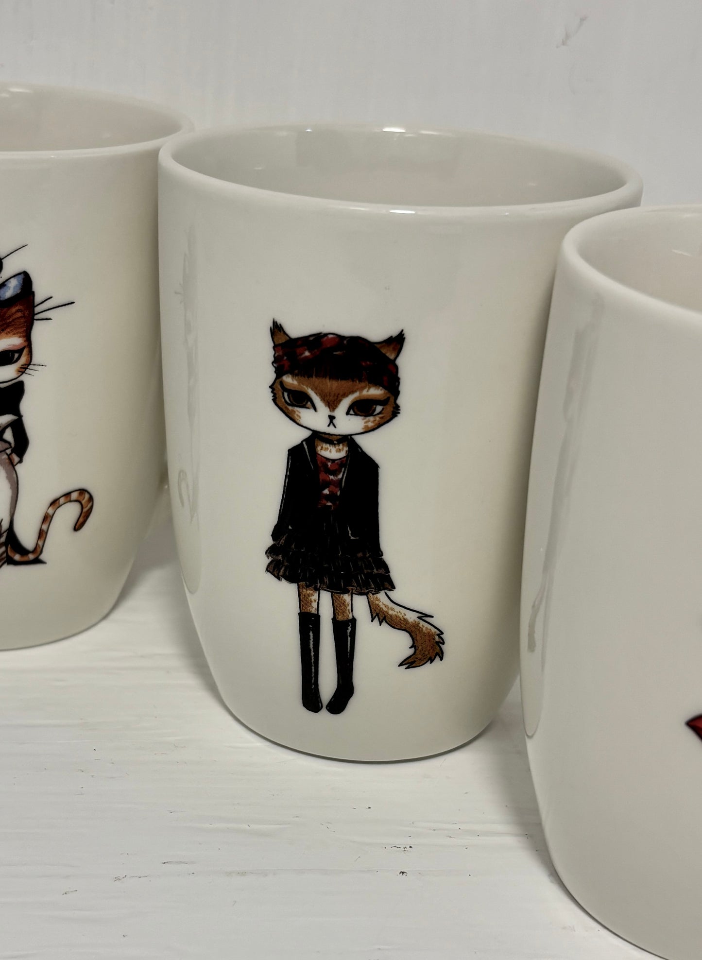 White mugs with cat-themed designs on a white surface