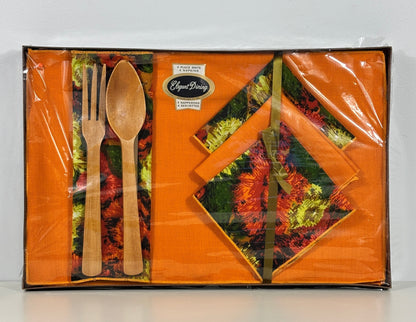 A boxed tableware set in clear plastic wrapping, featuring orange napkins with a floral autumn pattern and light wood-colored utensils on a white background.