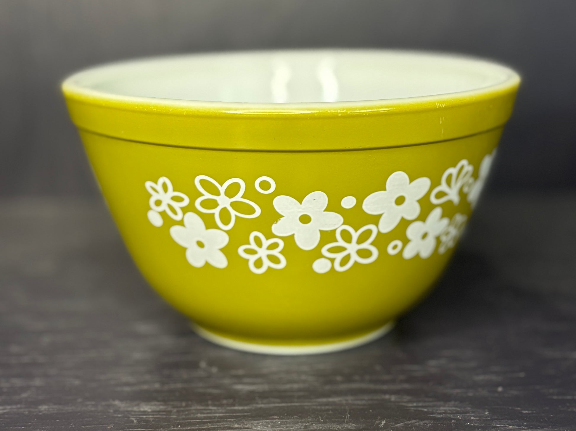 Green bowl with white floral patterns on a dark background
