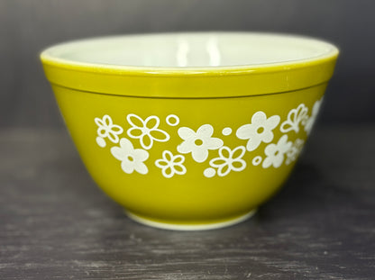Green bowl with white floral patterns on a dark background