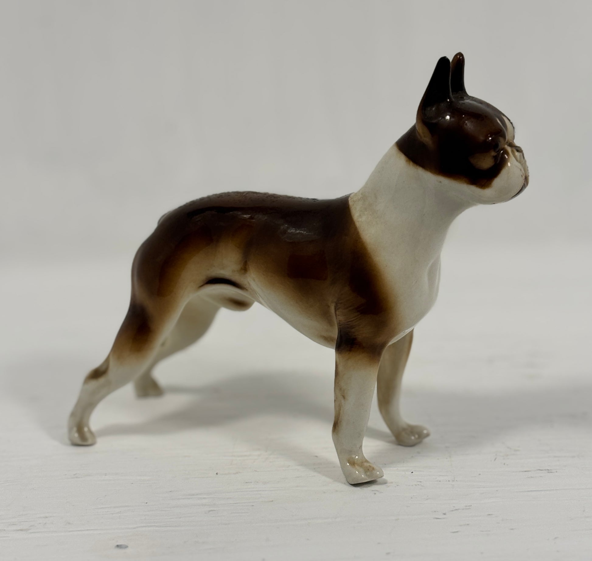 Dog figurine with brown and white coloration on a light gray background