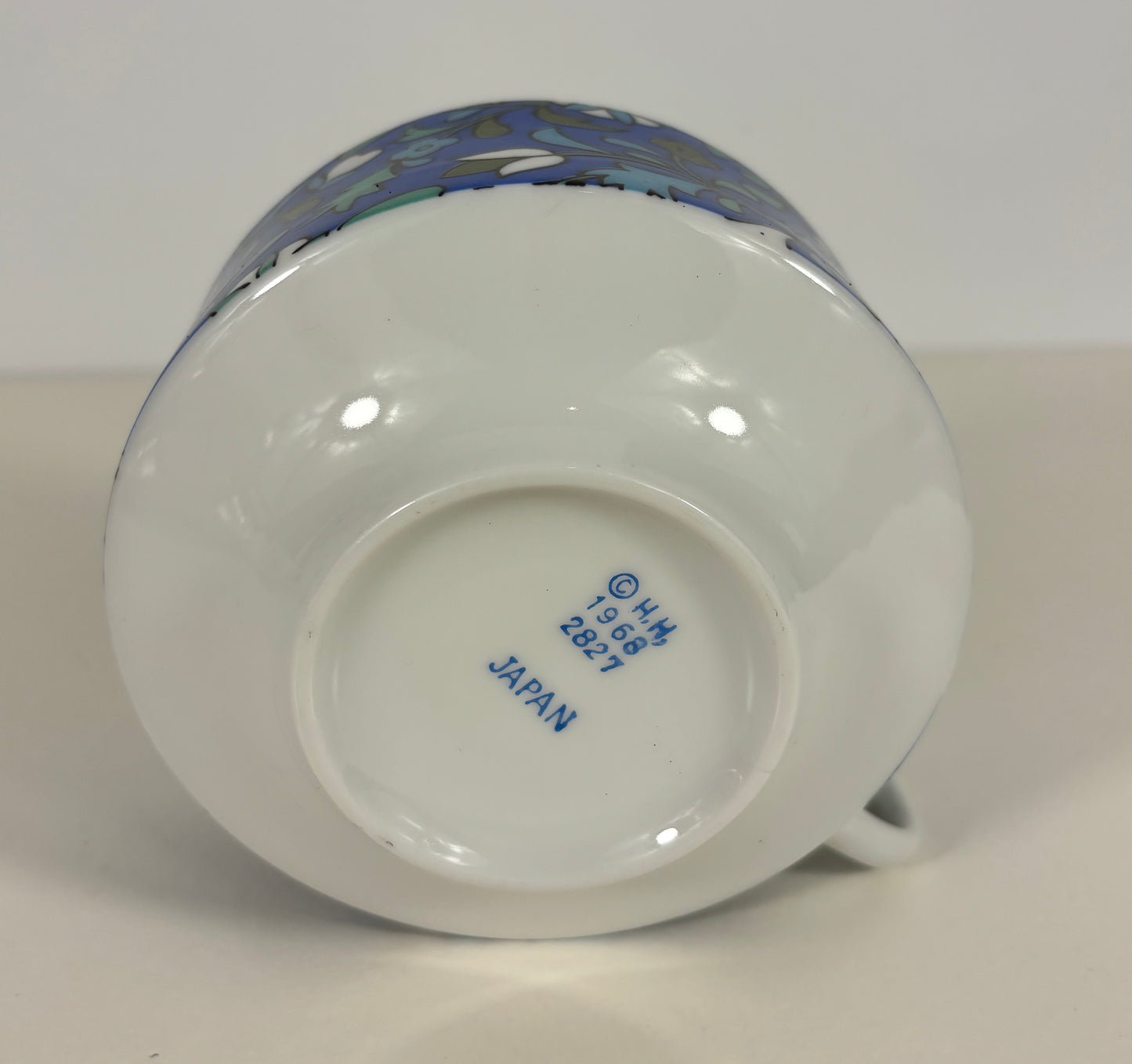Ceramic mug with a colorful design on the handle, brand name visible on the base.