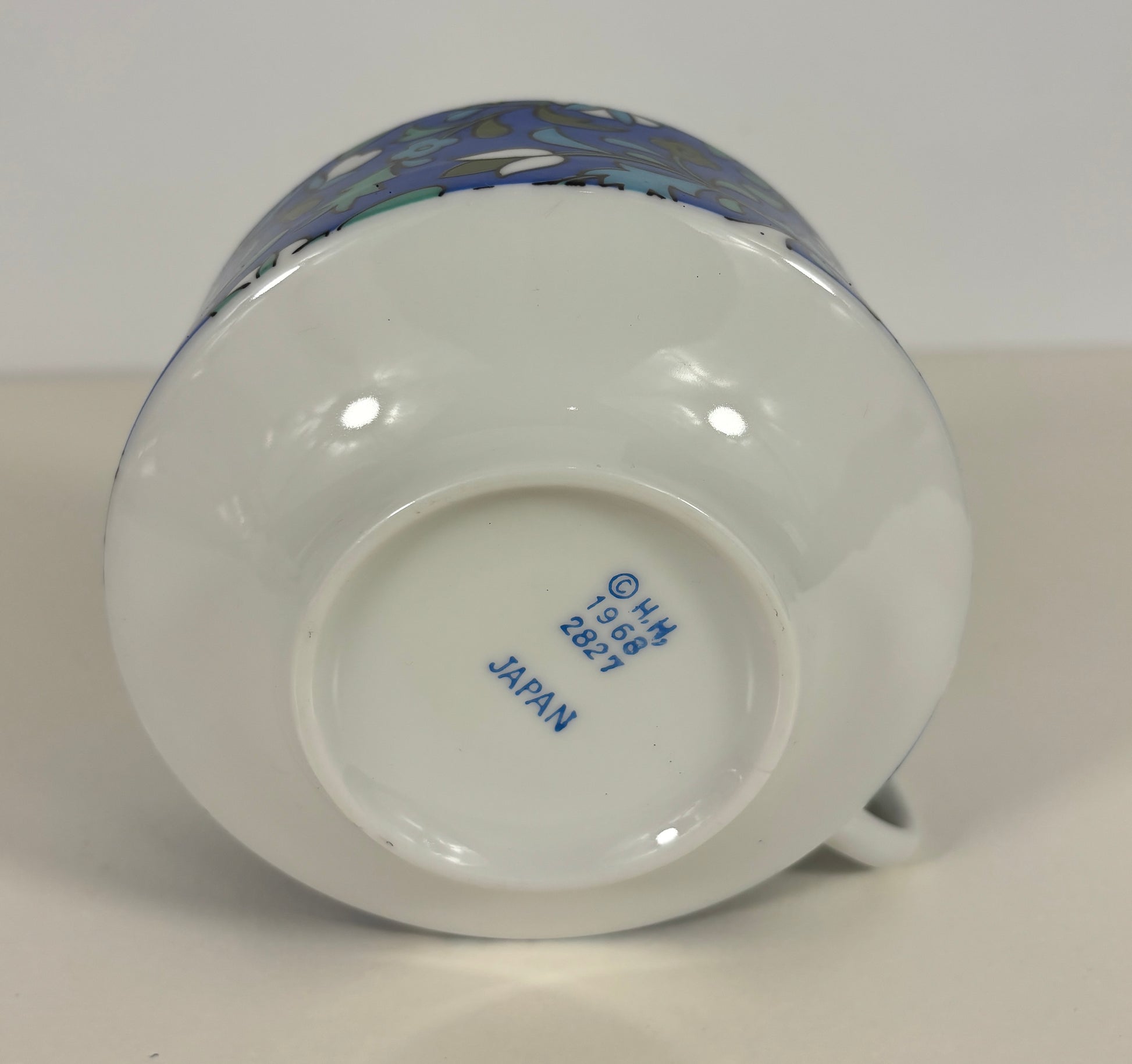 Ceramic mug with a colorful design on the handle, brand name visible on the base.