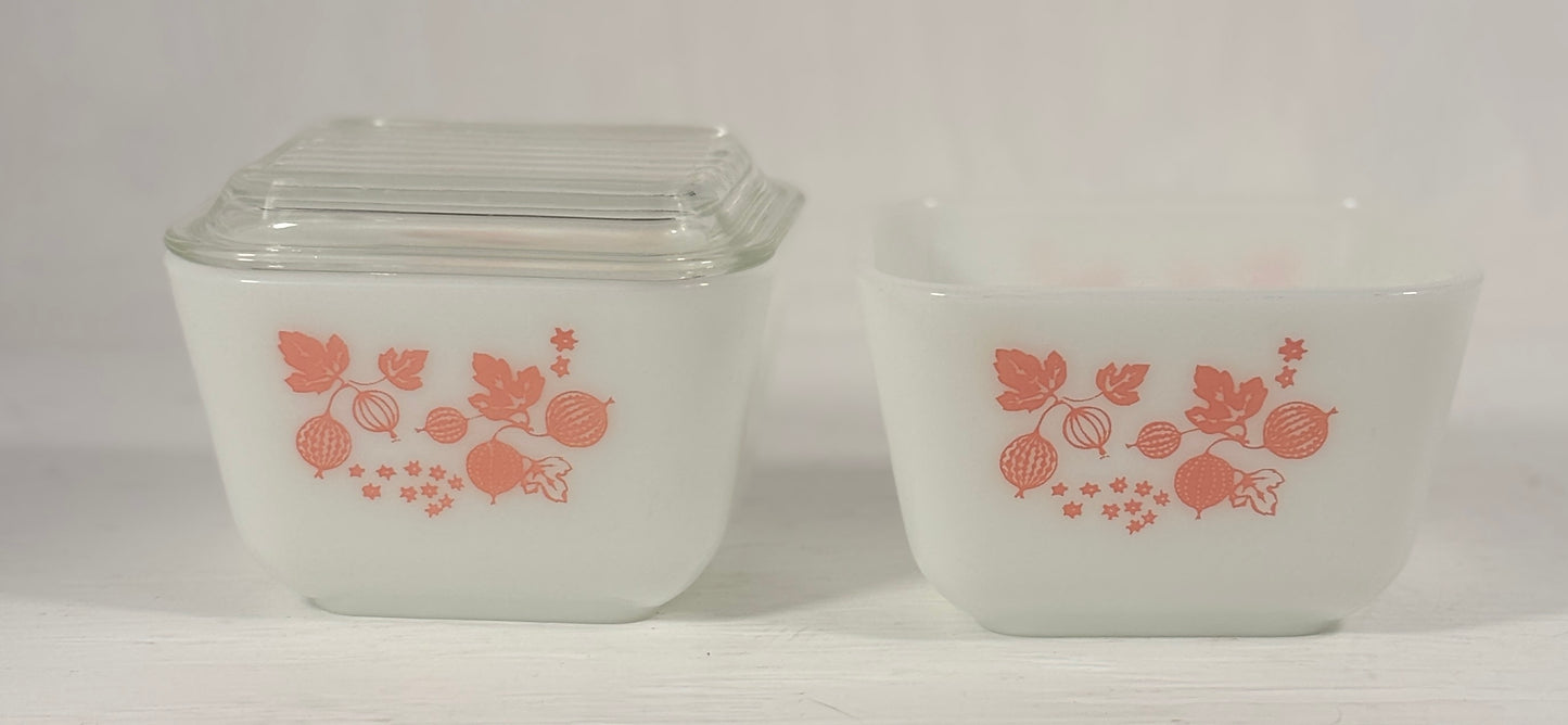 Two vintage glass containers with pink floral design on a white background