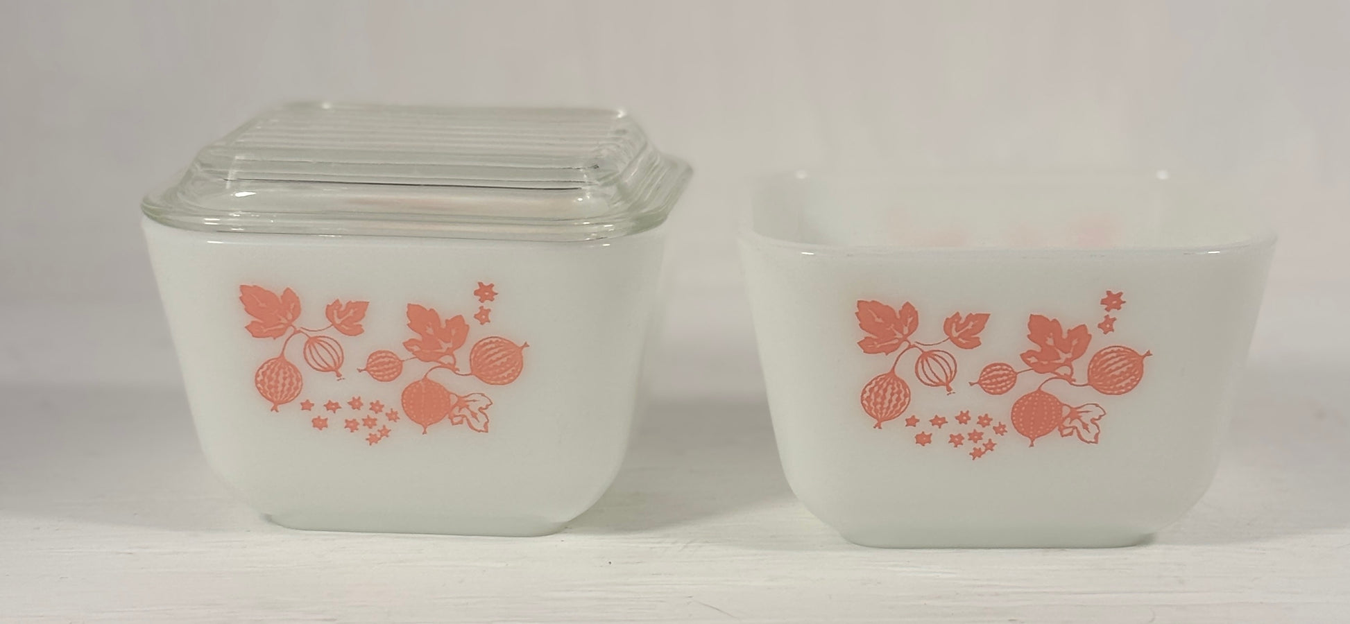 Two vintage glass containers with pink floral design on a white background