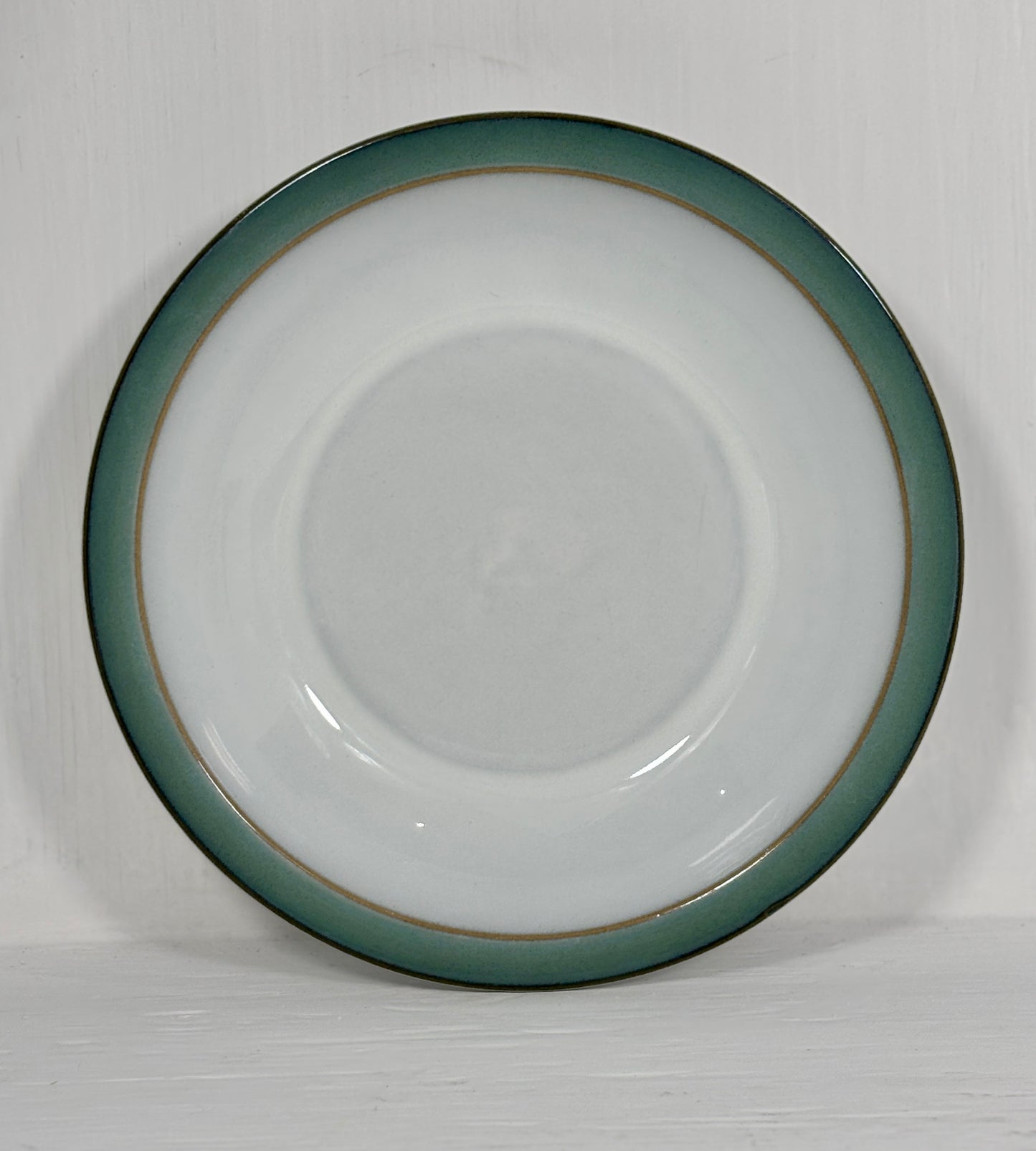 White ceramic plate with a green rim on a white background