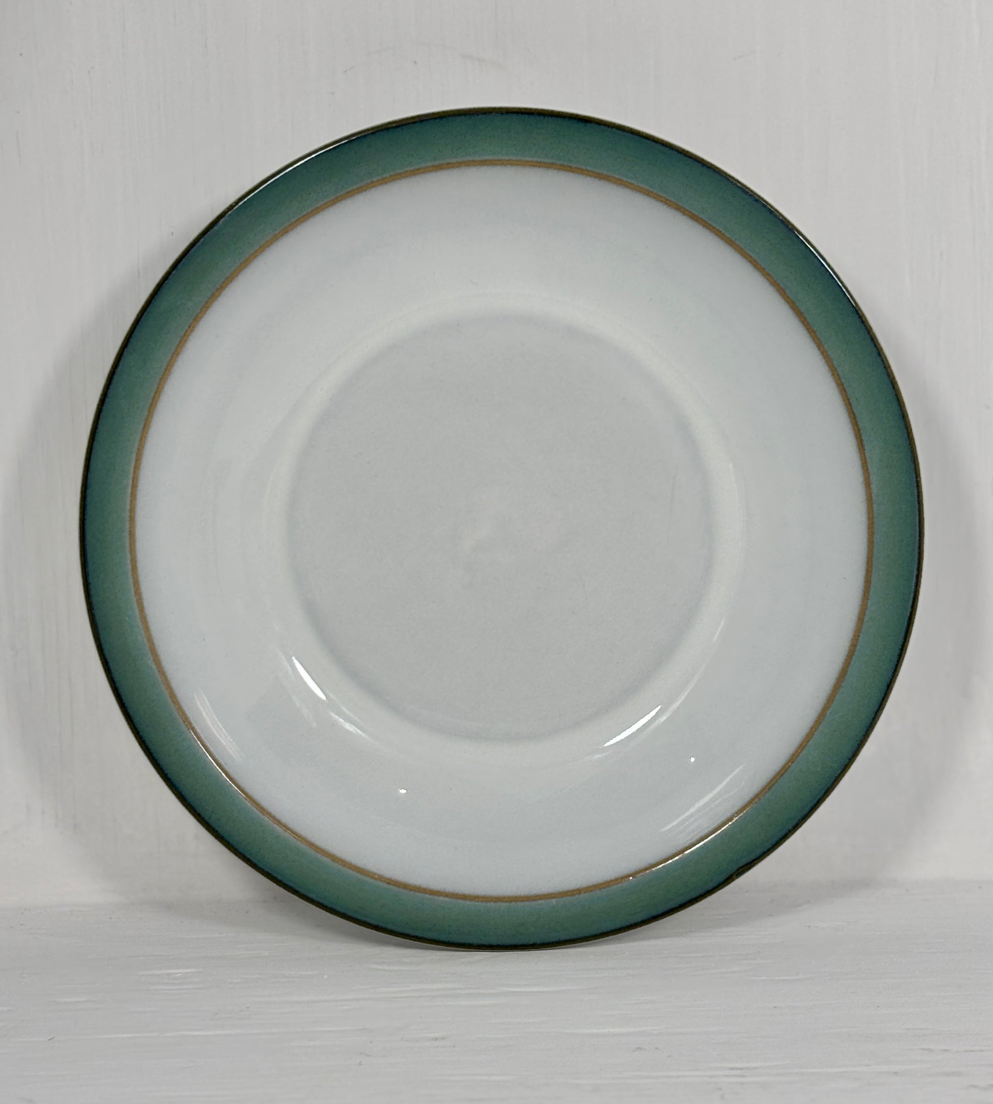 White ceramic plate with a green rim on a white background