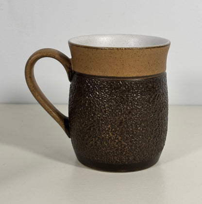 Brown textured ceramic mug on a light gray background
