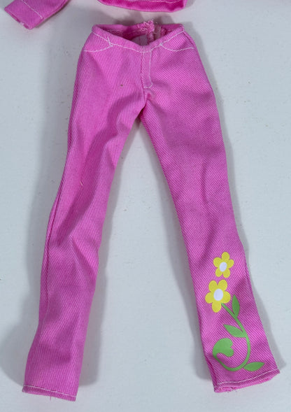 Pink doll pants with a textured fabric, featuring a yellow and white flower and green vine print on one leg, shown on a light gray background.