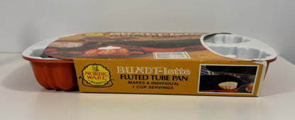 Nordic Ware Blanche-Jette fluted tube pan in its original retail packaging, featuring a gold and orange label with product details and a photo of baked food.
