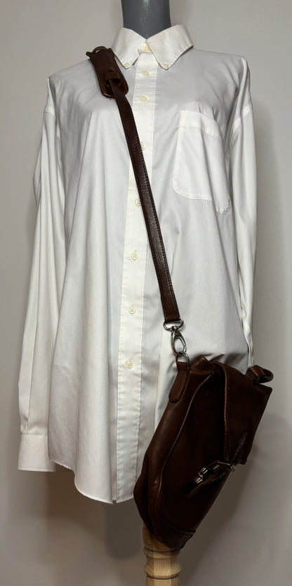 White shirt on a mannequin with a brown leather bag over its shoulder against a plain background