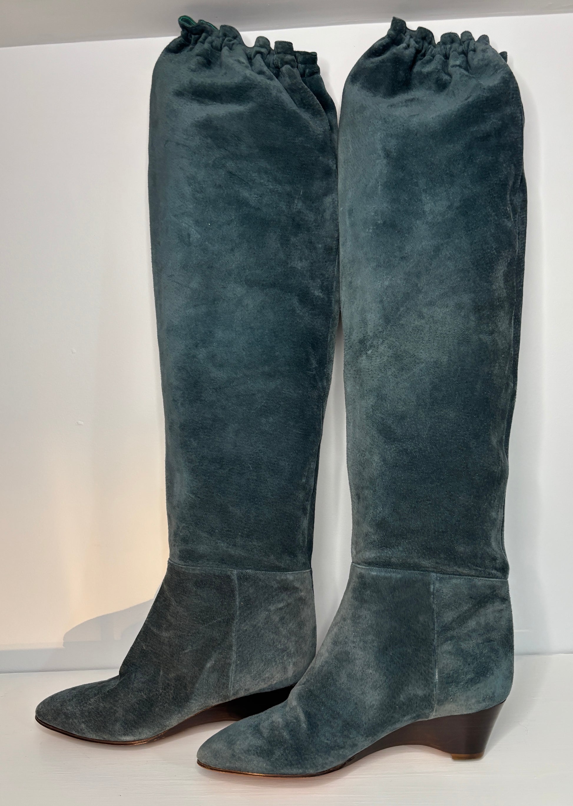 Pair of green suede knee-high boots on a white background
