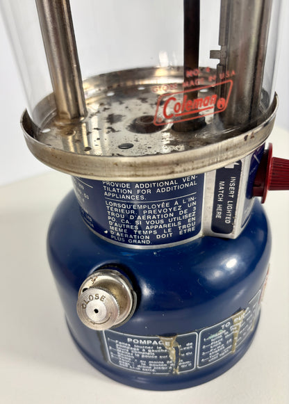 Close-up of a blue camping lantern with visible branding on a white background