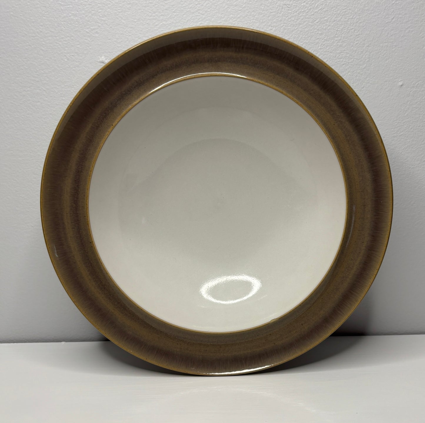 Round ceramic dish with brown rim on a white background